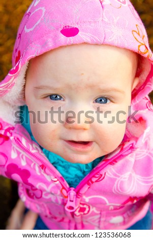 A young infant girl in pink is photographed outdoors for this child portrait.