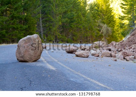 This national forest road is blocked by a land slide of rock and debris to where it is a hazard for drivers in cars.