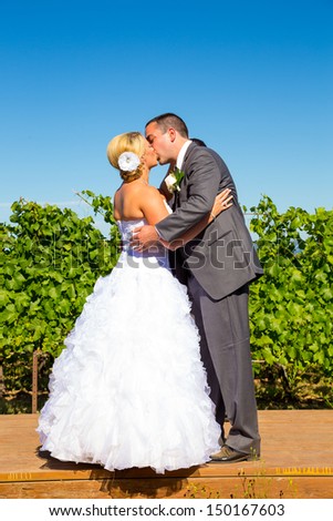 A bride and groom seal the deal with a kiss during their wedding day ceremony at a vineyard winery in Oregon.