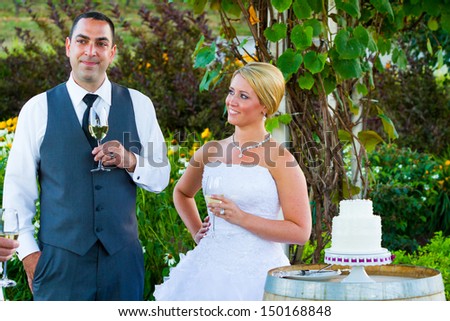 A bride and groom share a moment together while the best man and maid of honor toast them at their wedding reception.