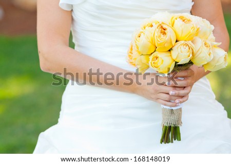 A beautiful bride in a white wedding dress holds her bouquet of flowers in her hand on her wedding day.