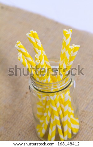 Yellow straws in a mason jar are part of the center pieces at this outdoor wedding.