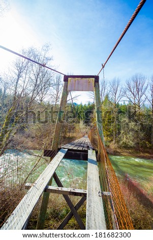 Very old swinging bridge crosses the Siuslaw River near Mapleton Oregon. This bridge was used to access a farm on the other side of the river but is no longer in use.