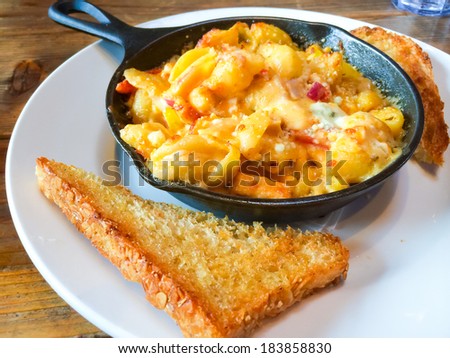 Fancy restaurant serves baked mac and cheese in a hot skillet with a side of Texas toast.