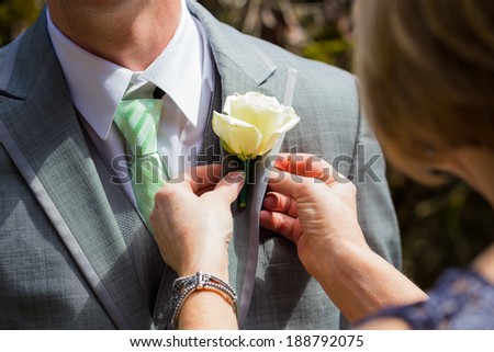 Florist pinning a boutineer on the groom on his wedding day.