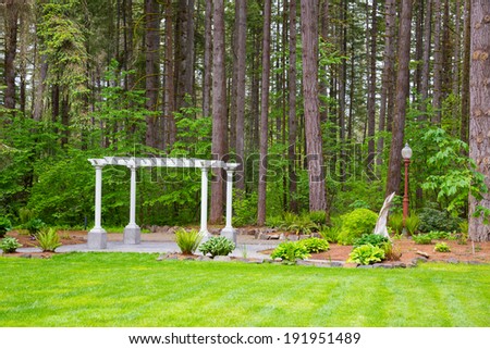 Outdoor wedding ceremony venue with white pergola set against some Oregon trees.