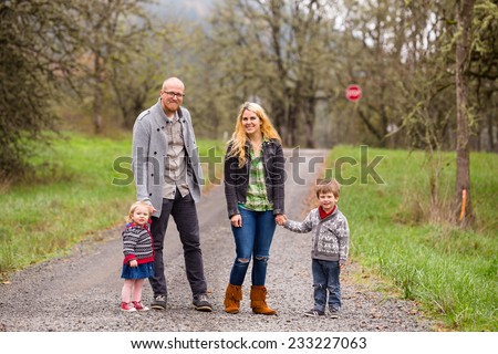 Family photo of a mother, father, and their two kids a boy and girl outdoors in the Fall.