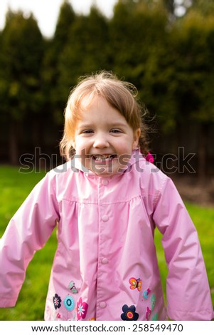 Portrait of a young girl at a park with a rain coat on. This lifetsyle photo was shot with natural light.