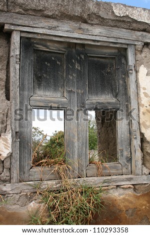 A broken window on a demolished house with plants growing through the window in Cotacachi, Ecuador