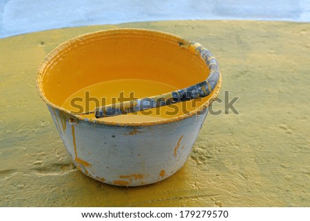 A steel paint bucket with yellow road paint on a street repair site in Cotacachi, Ecuador