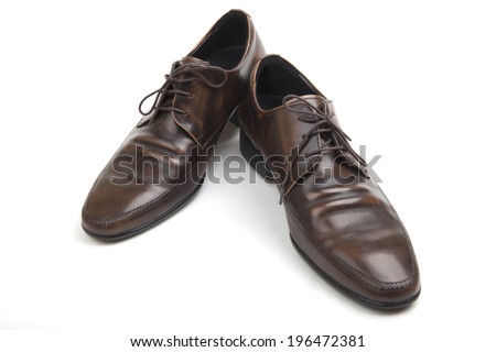 Pair of classic brown leather Polish mens shoes with laces and low heels for formal wear and dressing for the office, high angle on white
