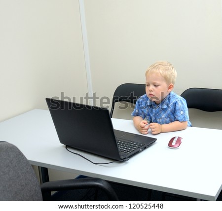 Small cute business boy with computer in office