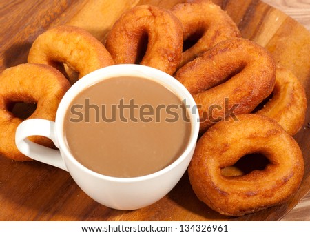 Coffee cup and oil donuts on a wooden plate.