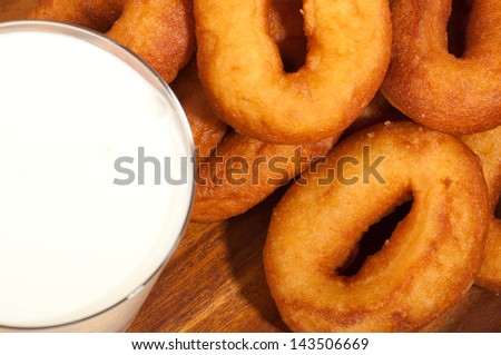 Oil donuts and glass of milk on a wooden plate.
