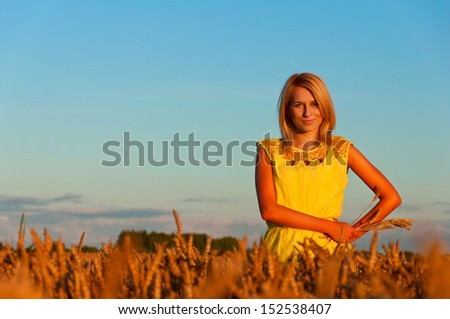 Happy woman in yellow dress  in golden wheat.