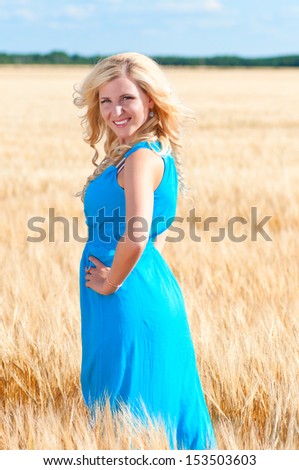 Happy woman in blue dress  in golden wheat.