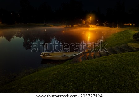 Lonely boat on lake with fog at night time