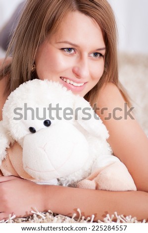 beautiful young woman wearing pajamas hugging her stuffed lamb