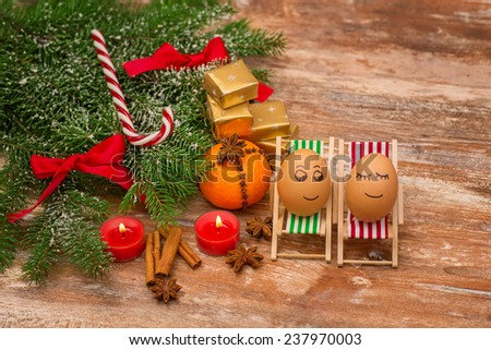 funny eggs on a beach chairs, Christmas tree, mandarine, gift and candles.  christmas background theme