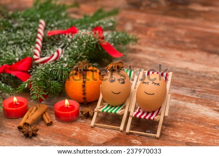 funny eggs on a beach chairs, Christmas tree, mandarine, and candles.  christmas background theme