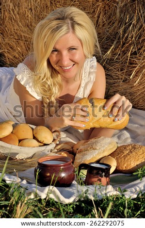 Happy woman posing with bread, milk and hay as background