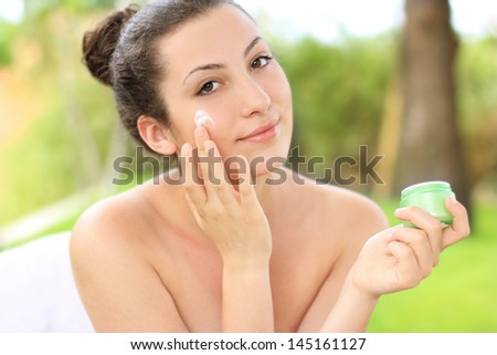 Gorgeous woman applying cream to her perfectly toned skin