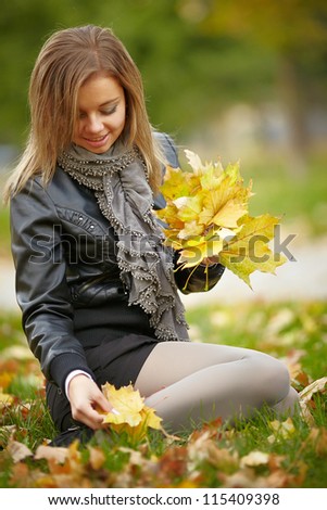 Beautiful girl in the autumn park collects leaves