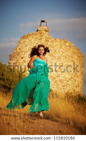 Girl floating on a mountain trail. Behind the back of the ruins of a tower of stone