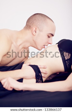 Beefy guy kissing a beautiful girl in the stomach in underwear