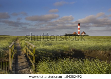 Lighthouse and a small bridge in the salt meadows at the germany north sea coast