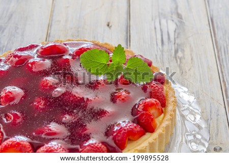 Homemade strawberry cake on a glass platter on a wooden table