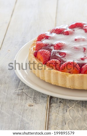 Homemade strawberry cake on a white platter on a wooden table