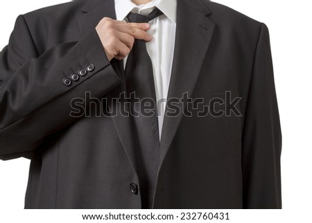 A Man in a black suit straightening his tie isolated on white background