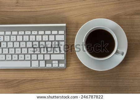 Modern keyboard and a cup of coffee on a wooden Desktop