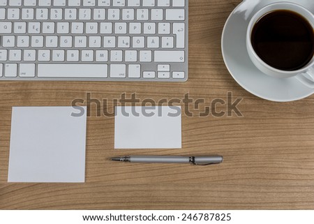 Modern keyboard a memo a business card a pen and a cup of coffee on a wooden Desktop