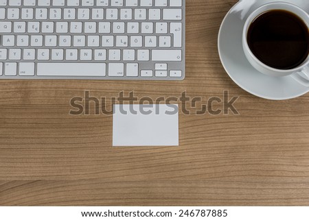 Modern keyboard a business card and a cup of coffee on a wooden Desktop
