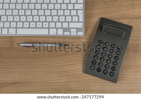 Modern keyboard and a calculator on a wooden Desktop