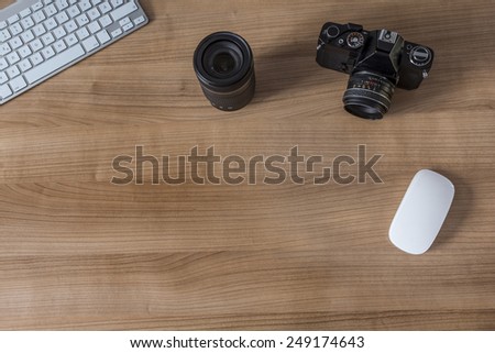 Modern keyboard and a vintage camera on a wooden desktop