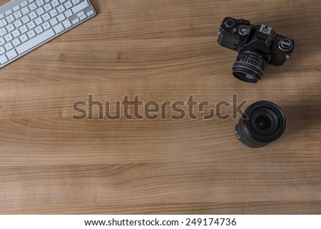 Modern keyboard and a vintage camera and a pen on a wooden desktop