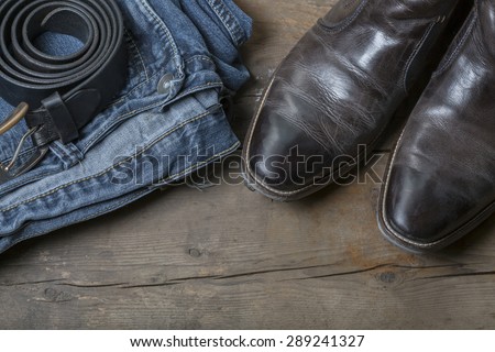Jeans, Belt and leather boots on a rustic wooden background