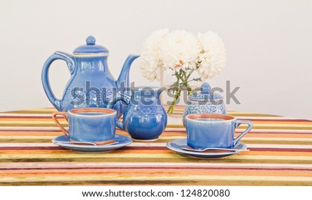 tea or coffee set on table with colorful line fabric in gray wall room