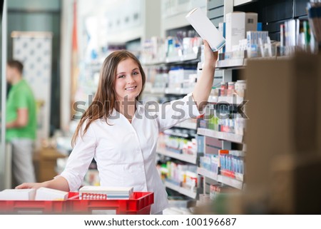 Portrait of female pharmacist keeping a box on shelf