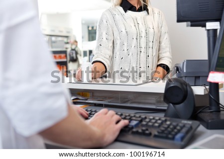 Mid-section of customer standing at checkout counter in drugstore