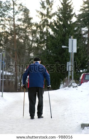 An old man walking on a snowy road with two canes