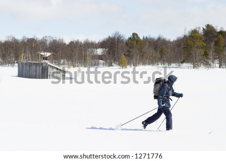 A skier with a large backpack on a wintery snow filled landscape.