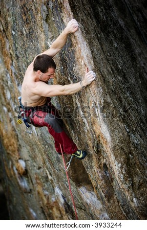 Male climber at the top of a very tall rock wall (crag)
