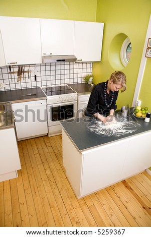 A young woman makes bread on the counter at home in the kitchen.