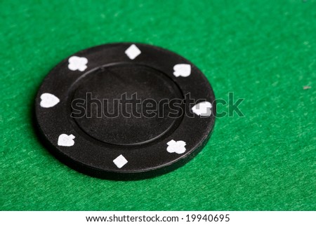 A black $100 poker chip on green felt