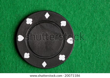 A black $100 poker chip on green felt