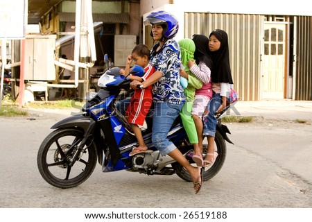 PAPUA, INDONESIA - CIRCA 2009: A family of four ride on a scooter.  This is a very popular means of transportation.